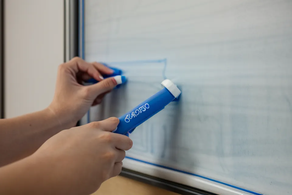 A retired teacher's hand holding a whiteboard marker, an early sign of aging vision changes in the classroom
